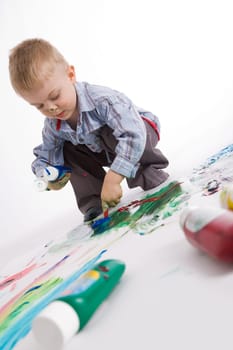 Photo of cute preschooler painting something with colorful gouache