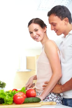Portrait of pretty female cooking salad with her husband near by