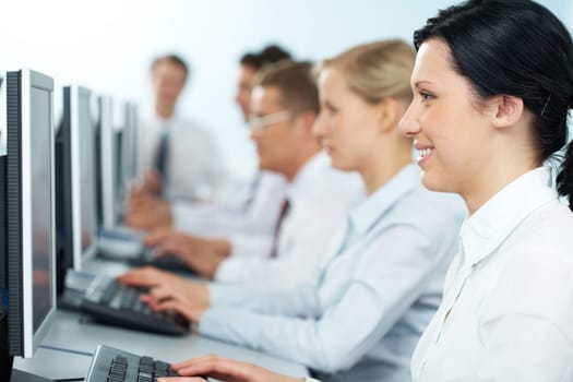 Close-up of a happy businesswoman working on computer among the others