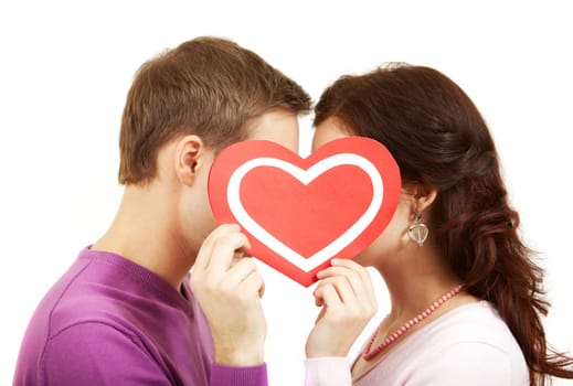 Two young people kissing behind a paper heart