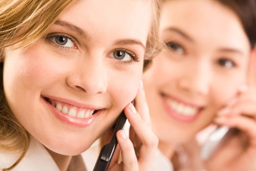 Close-up of pretty woman with cellular phone looking at camera with smile