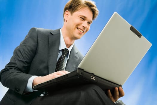 Successful young smiling businessman sees a plan the decision of a question in the laptop