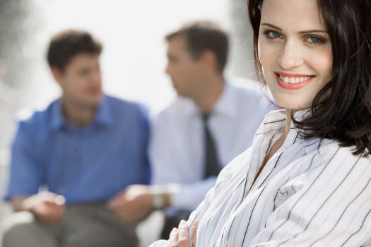 Portrait of successful young woman on the background of two businesspeople