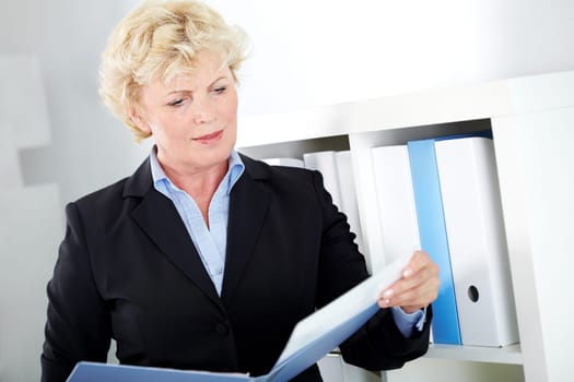 Portrait of middle aged businesswoman reading paper in office