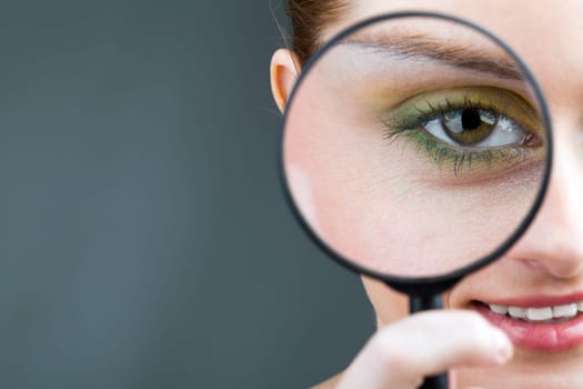 Close-up of young woman looking through magnifying glass