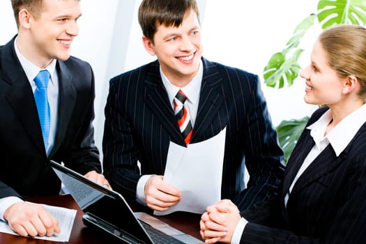 Three people gathered together around the table and discuss ideas at business meeting