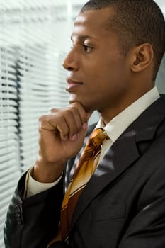 Serious businessman looking through venetian blind in office