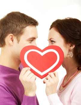 Two young people looking at each other behind a paper heart