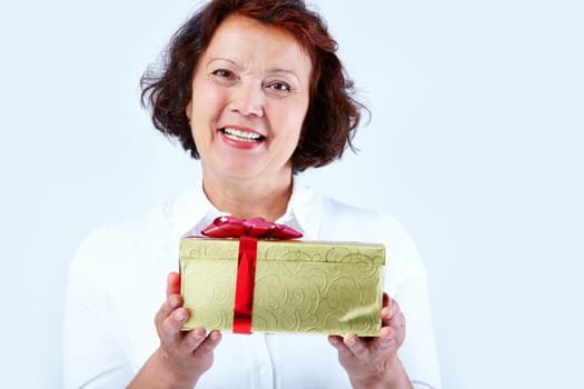 Portrait of middle-aged female looking at camera with smile and showing golden giftbox