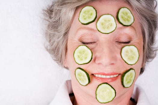 Face of mature woman with cucumber slices on it