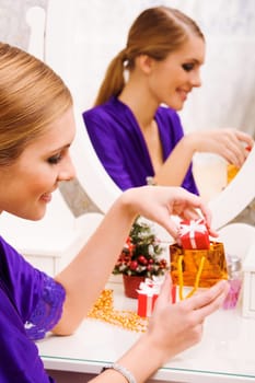 Portrait of happy girl putting small giftbox into golden package
