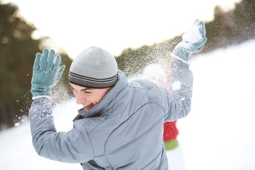 Image of attractive young man laughing while under snowball bombing