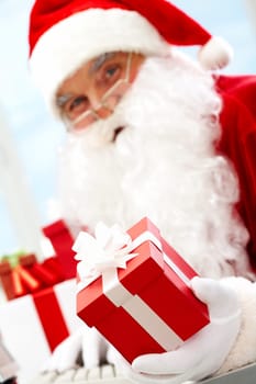 Photo of happy Santa Claus with red giftbox looking at camera