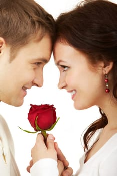 Close-up of two young people looking at each other and holding a rose