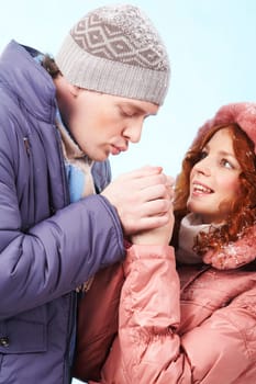 Portrait of careful young man warming up his girlfriend hands