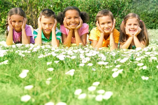 Portrait of cute kids lying on green grass and looking at camera