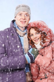 Portrait of happy young couple together looking at snowfall