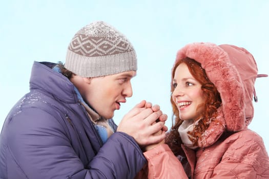 Portrait of careful young man warming up his girlfriend hands