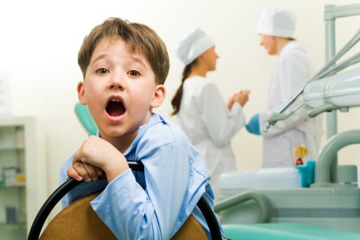 Portrait of happy boy in dentist room on background of two doctors