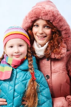 Happy mother and her daughter looking at camera with smiles