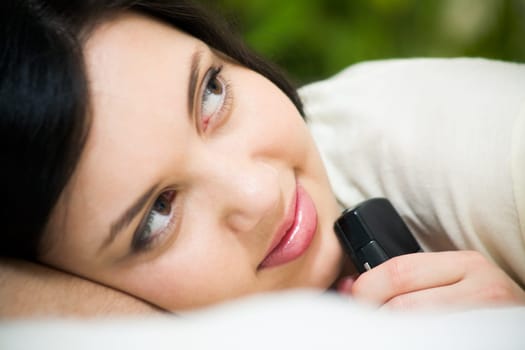 Face of charming girl holding telephone by her chin and looking aside