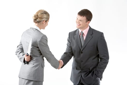 Portrait of business partners handshaking while female holding knife behind her back