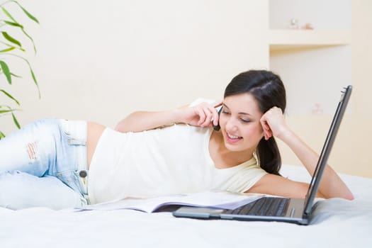 Photo of attractive teenage girl talking on the phone while looking into a book