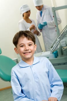 Portrait of happy boy in dentist room on background of two doctors