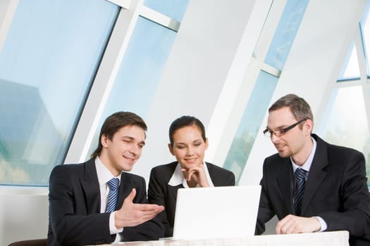 Portrait of executive employees looking at laptop monitor with smiles and communicating