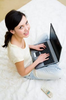 View from above of smart teenager pressing laptop buttons and looking at camera