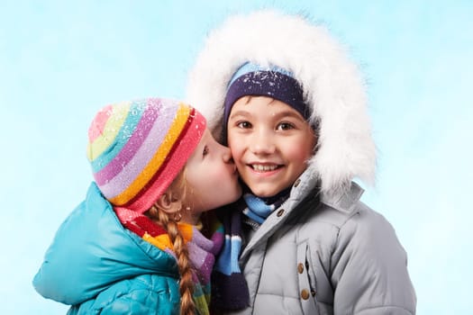 Portrait of happy child smiling at camers while being kissed by pretty girl