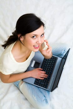Above shot of friendly girl speaking on the phone and typing on laptop