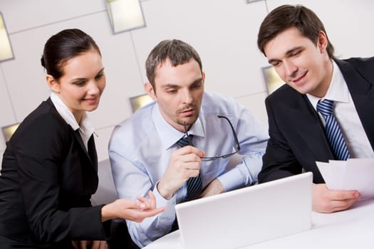 Portrait of executive employees looking at laptop monitor with pensive boss between them and discussing new project