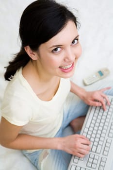 Busy girl looking at camera with smile while pressing keyboard buttons