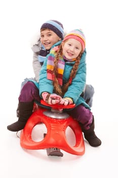 Happy siblings looking at camera while sitting on sledge