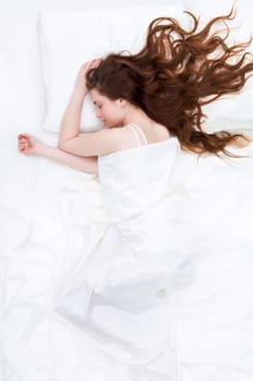 Image of peaceful girl lying on linen bed under satin cloth and dreaming