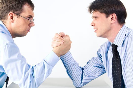 Portrait of two businessmen sitting opposite each other elbowing on the table with their arms grappled in fight