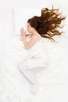 Above view of sleeping woman under white satin sheet
