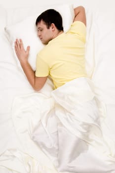 Shot from above of tranquil male sleeping in comfortable bed at night