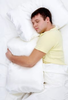 Photo of handsome man sleeping and holding soft white pillow