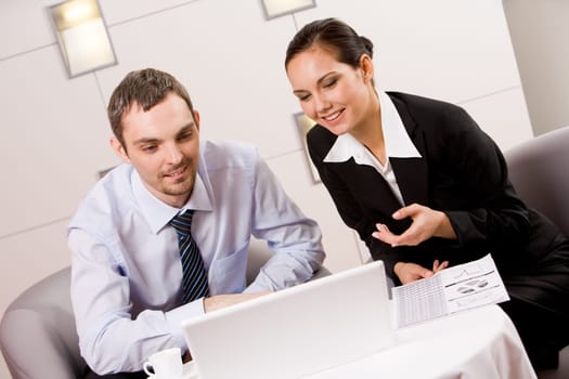 Portrait of executive employees looking at laptop monitor with smiles and speaking about new project