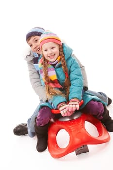 Happy siblings looking at camera while sitting on sledge