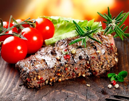 A grilled serving of succulent tender peppered steak garnished with lettuce, tomato and fresh rosemary herbs