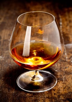 Glowing goblet of rich cognac on a wooden bar counter on a relaxing night out with friends