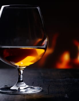 Brandy snifter warming before a glowing fire on an enjoyable and entertaining night out on the town