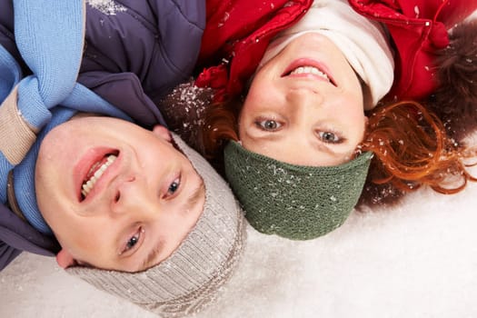 Above shot of happy young couple lying in snow