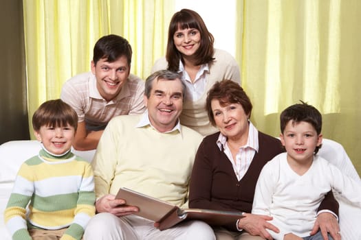 Portrait of happy family of six sitting on sofa and looking at camera