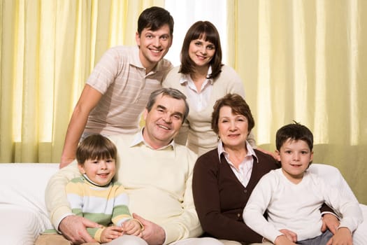 Portrait of senior and young couples with their children looking at camera at home