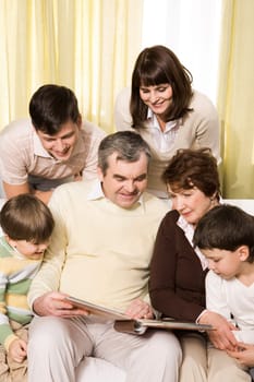 Portrait of senior and young couples with their children looking at family photos