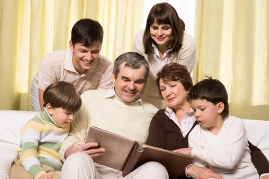 Portrait of senior and young couples with their children looking at family photos